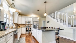 A modern kitchen with white cabinetry, stainless steel appliances, a granite countertop, and a wooden floor. - Limpy Creek Access! Family Retreat in Grants Pass (Grants Pass)