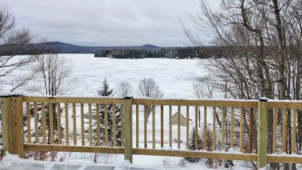 A wooden deck with a view of a snowy landscape and trees. - Old Forge Getaway! Cozy Base for All-season Fun (Old Forge)