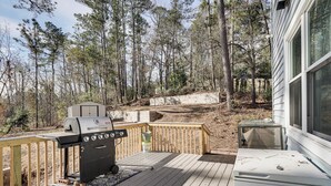 A deck with a barbecue grill, a trash can, and a window overlooking a forested area. - 8 Mi to Augusta National: Group Getaway w/ Deck (Augusta)