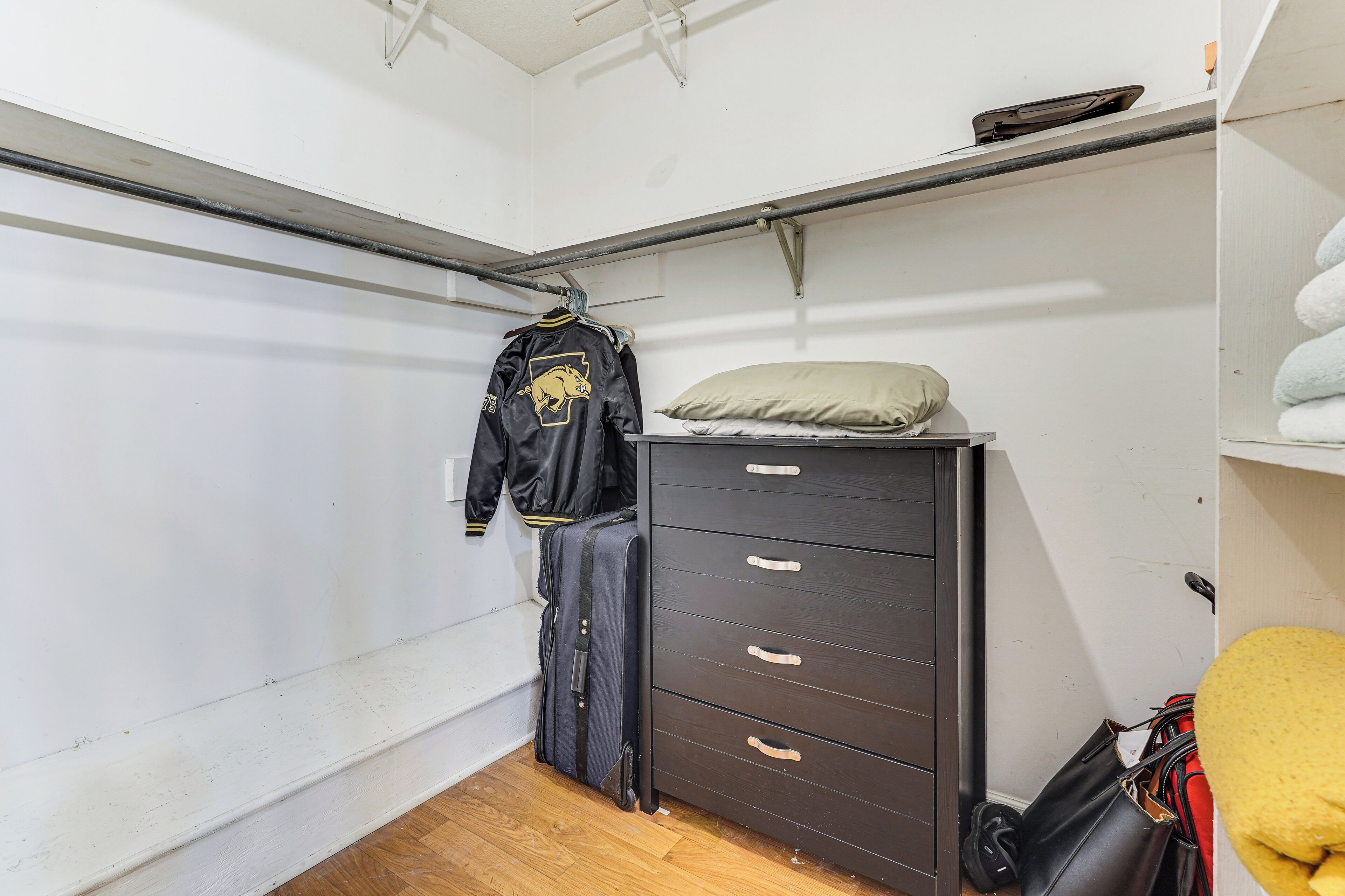 Une petite pièce comprenant un lit, une commode et un porte-manteau.