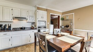 A kitchen with white cabinets, a wooden dining table, and a microwave. - 8 Mi to Augusta National: Group Getaway w/ Deck (Augusta)