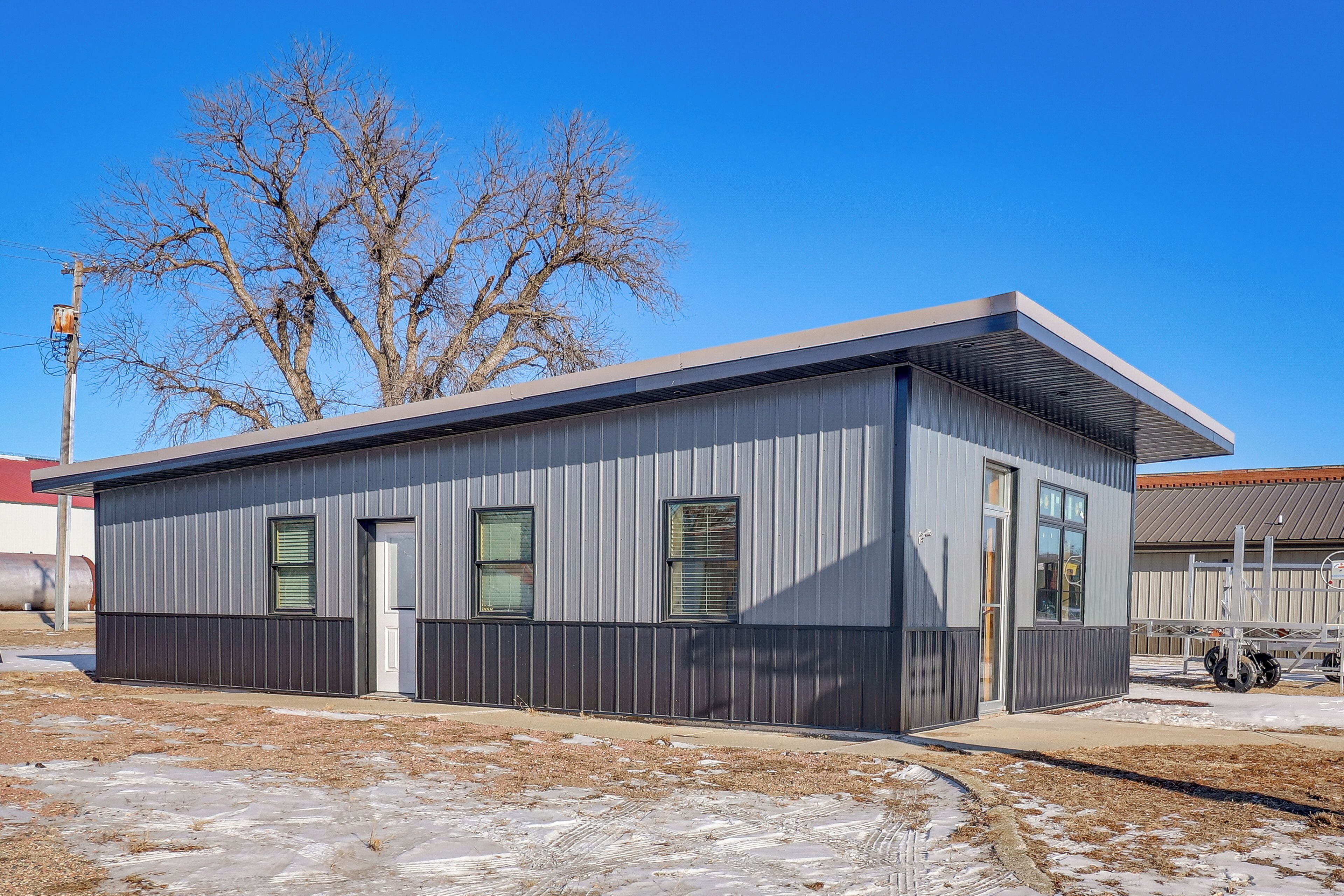 A modern, single-story building with a flat roof, large windows, and a door.
