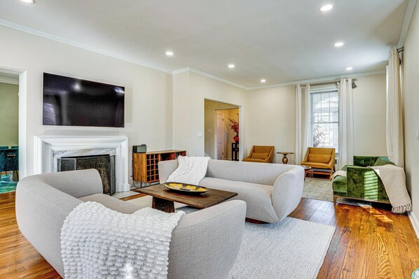 A modern living room with a fireplace, sofas, a coffee table, and a television mounted on the wall. - Explore Orange & Nyc! Luxury Family Home w/ Deck (Orange)