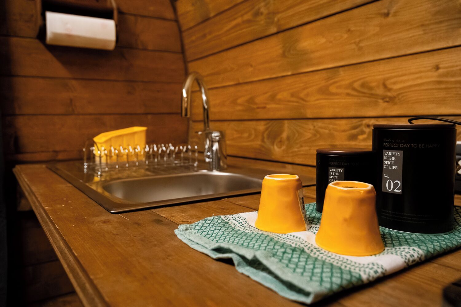 L’intérieur d’une cabane en bois, avec un évier, deux bougies et un chandelier.