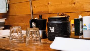 A kitchen counter with a coffee maker, a jar labeled "CAFFE'," and two glasses.