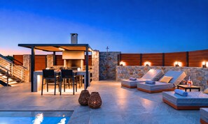 Una terrazza sul tetto con un muro in pietra, posti a sedere all'aperto e una piscina.