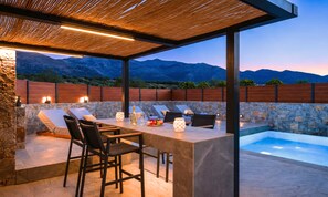 Une terrasse extérieure avec un mur en pierre, une piscine et une vue sur les montagnes.