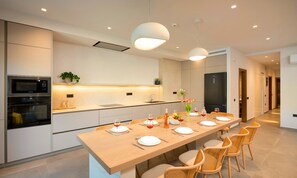 A modern kitchen with built-in appliances, a dining area with a long table set for six, and a hallway leading to other rooms. - Sissi Lux Kappa Villa Private Pool (Sisi)