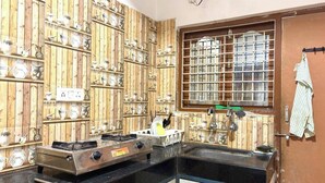 Una cucina con pareti in legno, un fornello a gas, un lavello e una finestra con inferriate.