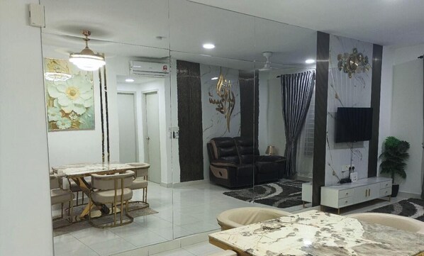 A modern living room with a dining area, a sofa, a TV, and a decorative wall. - HDIman Homestay Putrajaya KLIA view with Netflix Disney Sauna and Swimming Pool (Sepang)