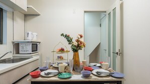 A compact kitchenette with a microwave, sink, and a small dining table set for four.