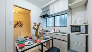 A compact kitchen with a dining table set for four, a microwave, a sink, and a small refrigerator.