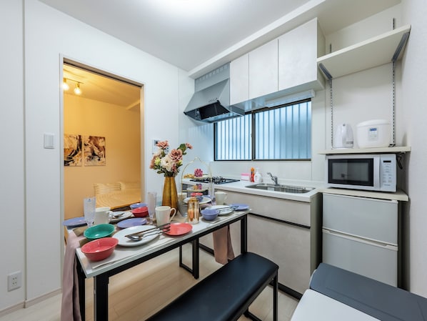 A compact kitchen with a dining table set for four, a microwave, a sink, and a small refrigerator.