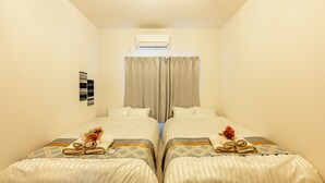 A twin room with two beds, a ceiling fan, and an air conditioning unit.
