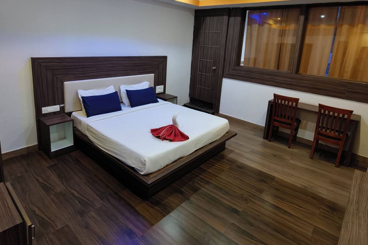 A modern hotel room with a large bed, bedside tables, a desk, and chairs.