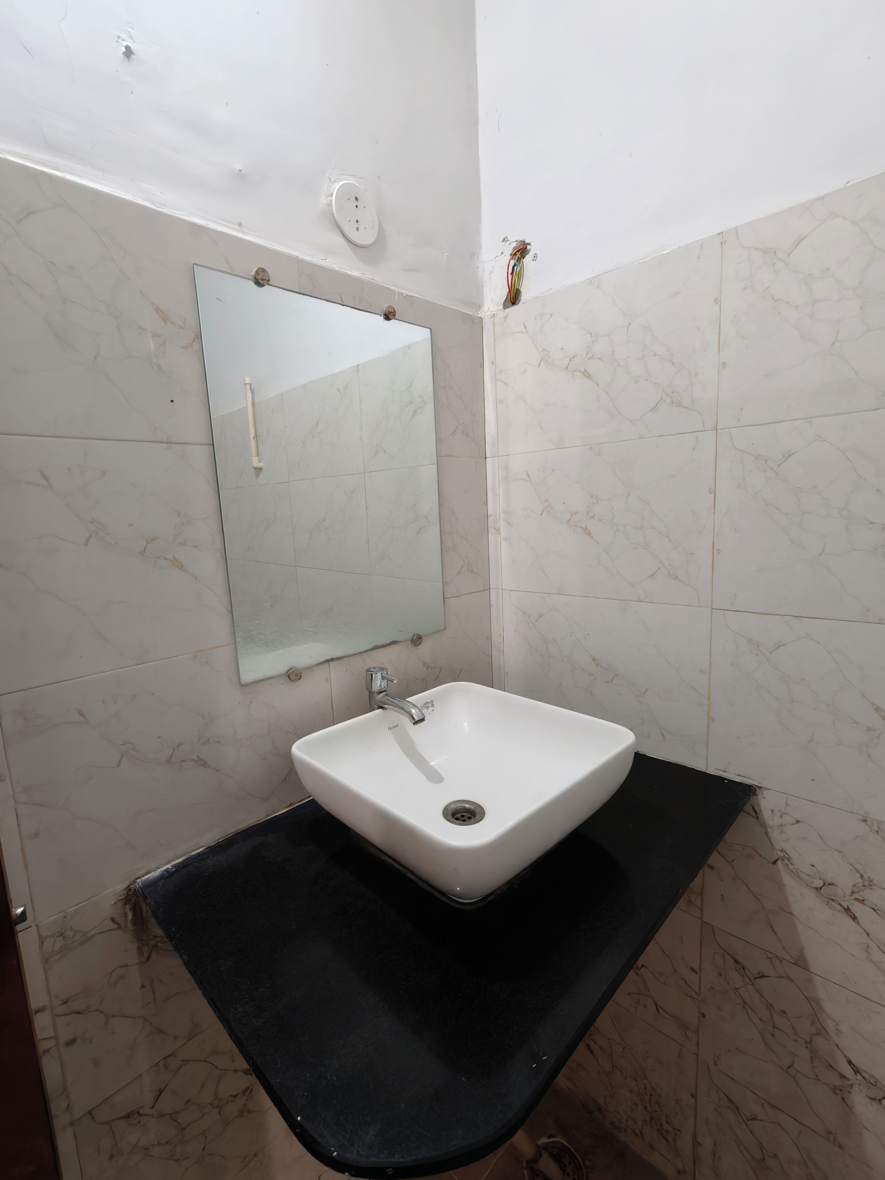 A bathroom with a white sink, a mirror, and a black countertop.
