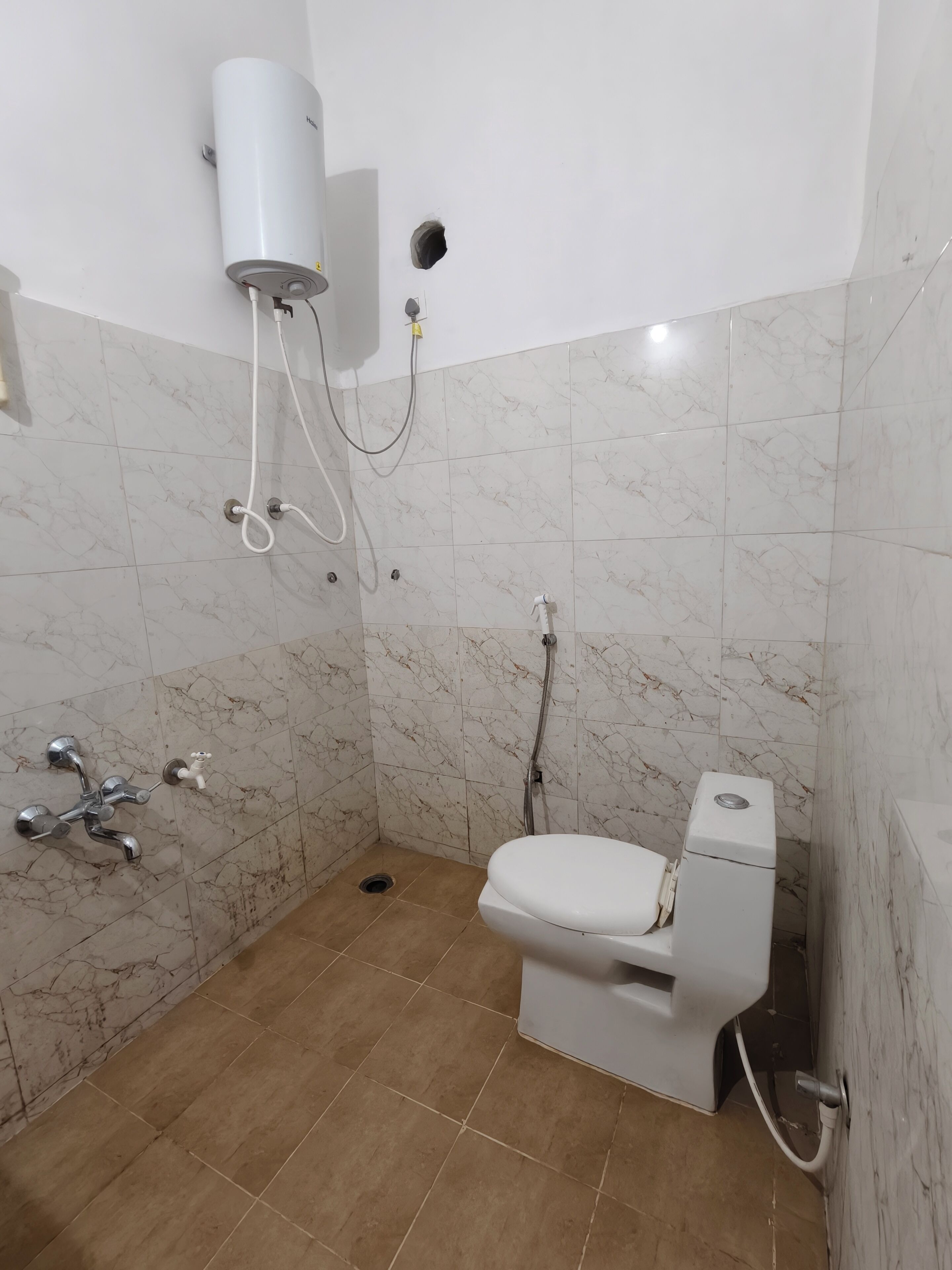 Une salle de bain équipée de toilettes, d’une douche et d’un chauffe-eau.
