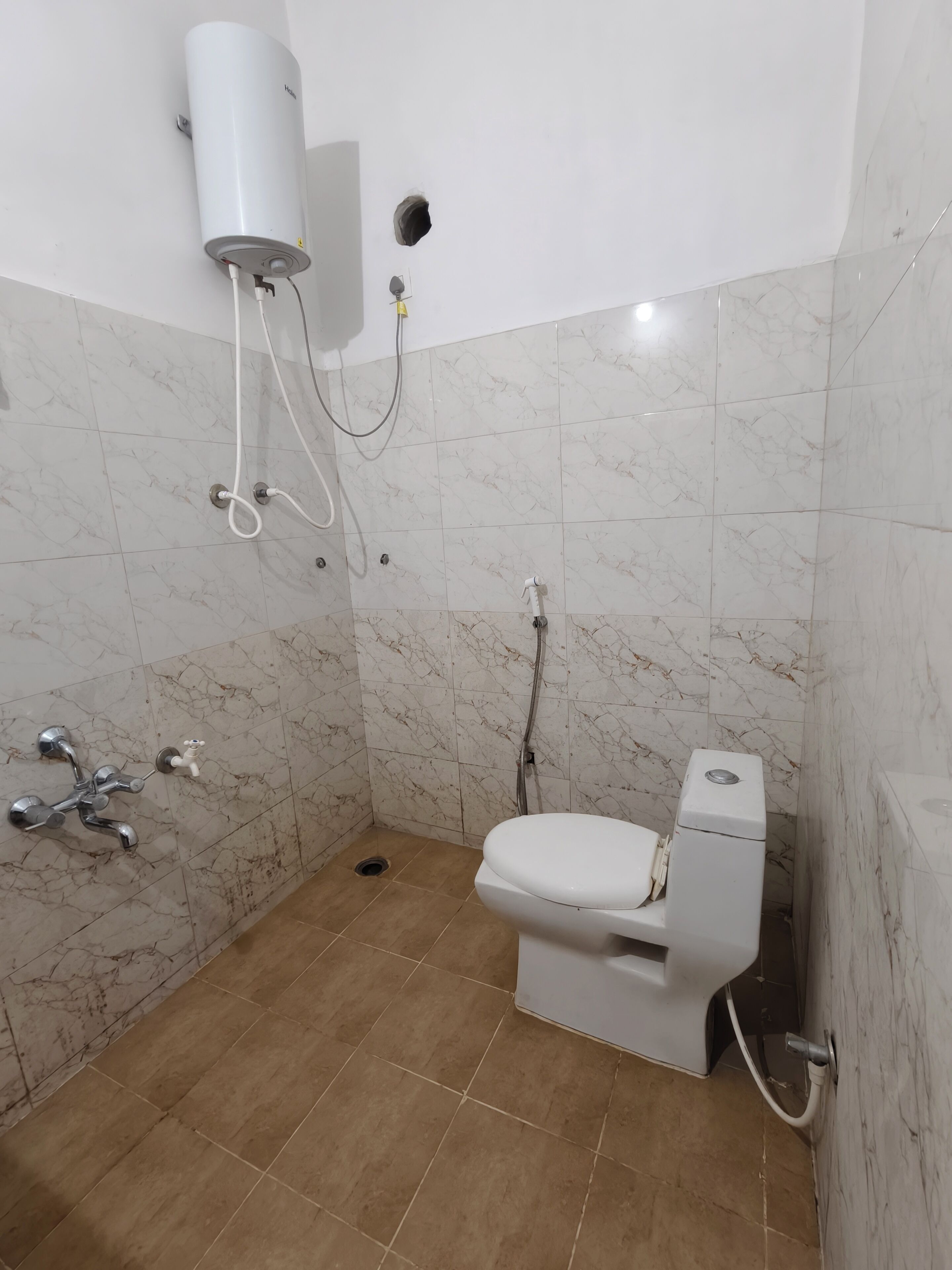 A bathroom with a toilet, a shower, and a water heater.
