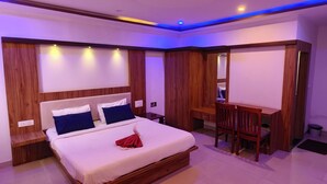 Une chambre moderne comprenant un lit, un bureau et un coin salon, avec un lambris en bois et un éclairage encastré.