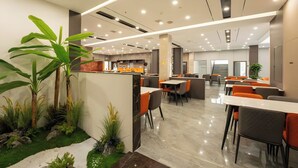 A modern indoor dining area with tables and chairs, a counter, and decorative plants. - Zhangjiajie Yunxi Scenic Hotel (Zhangjiajie)
