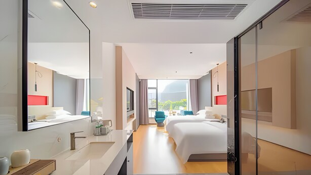 A modern hotel room with a large bed, a desk, a mirror, and a view of the outdoors. - Zhangjiajie Yunxi Scenic Hotel (Zhangjiajie)