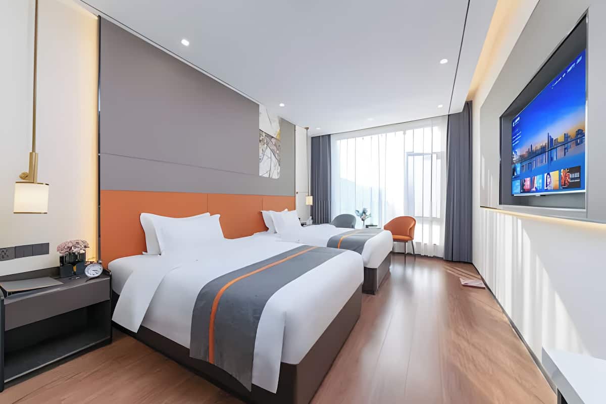 A modern hotel room with two beds, a TV, a desk, and a chair.