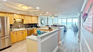 A modern kitchen with wooden cabinets, stainless steel appliances, and a central island. - Shoreline Towers 3103 2 Bedroom Condo (Destin)