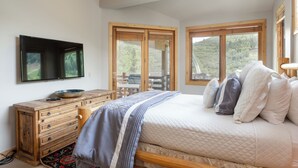 A bedroom with a bed, a wooden dresser, a television, and large windows offering a view of the outdoors. - 503 - Four Bedroom with Spa Trail's End Lodge 4 Condo (Park City)