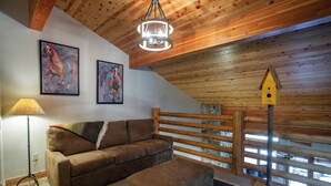 A cozy living room with a brown sofa, a small ottoman, a lamp, and two framed paintings on the wall. - 503 - Four Bedroom with Spa Trail's End Lodge 4 Condo (Park City)