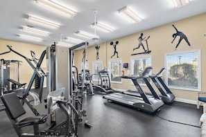 A gym with various exercise equipment, including treadmills and weight machines, and large windows with blinds. - Shoreline Towers 2031 3 Bedroom Condo (Destin)