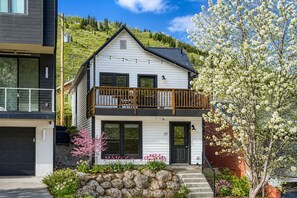 Ein zweistöckiges Haus mit Balkon, Garage und einem gepflegten Garten mit Steinen und blühenden Pflanzen.