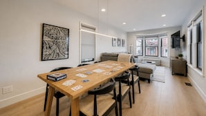 A dining area with a wooden table set for a game, a sofa, and a kitchen in the background. - Pet Friendly! Elevation 25 2 Bedroom Home (Park City)