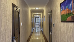 A long, well-lit hallway with patterned wallpaper, doors, and a framed picture on the wall.