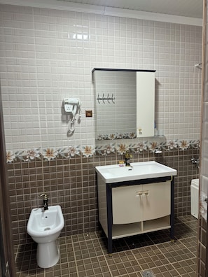 A bathroom with a white sink, a mirror, and a hairdryer on the wall.