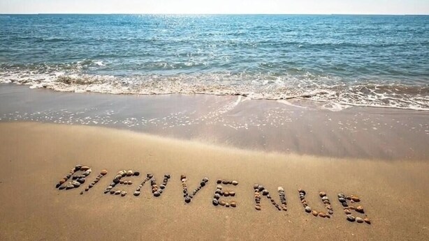 A beach with the words "BIENVENUS" written in stones.