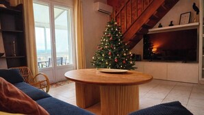 A cozy living room with a wooden coffee table, a blue sofa, and a Christmas tree.