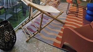 A balcony with a view of the beach, wicker furniture, and a cactus plant.