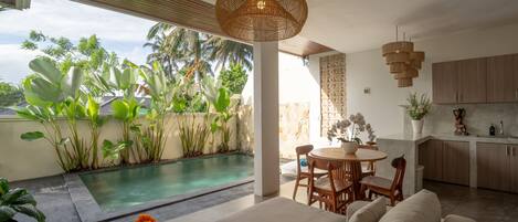 A modern living area with a pool, outdoor seating, and a kitchen.