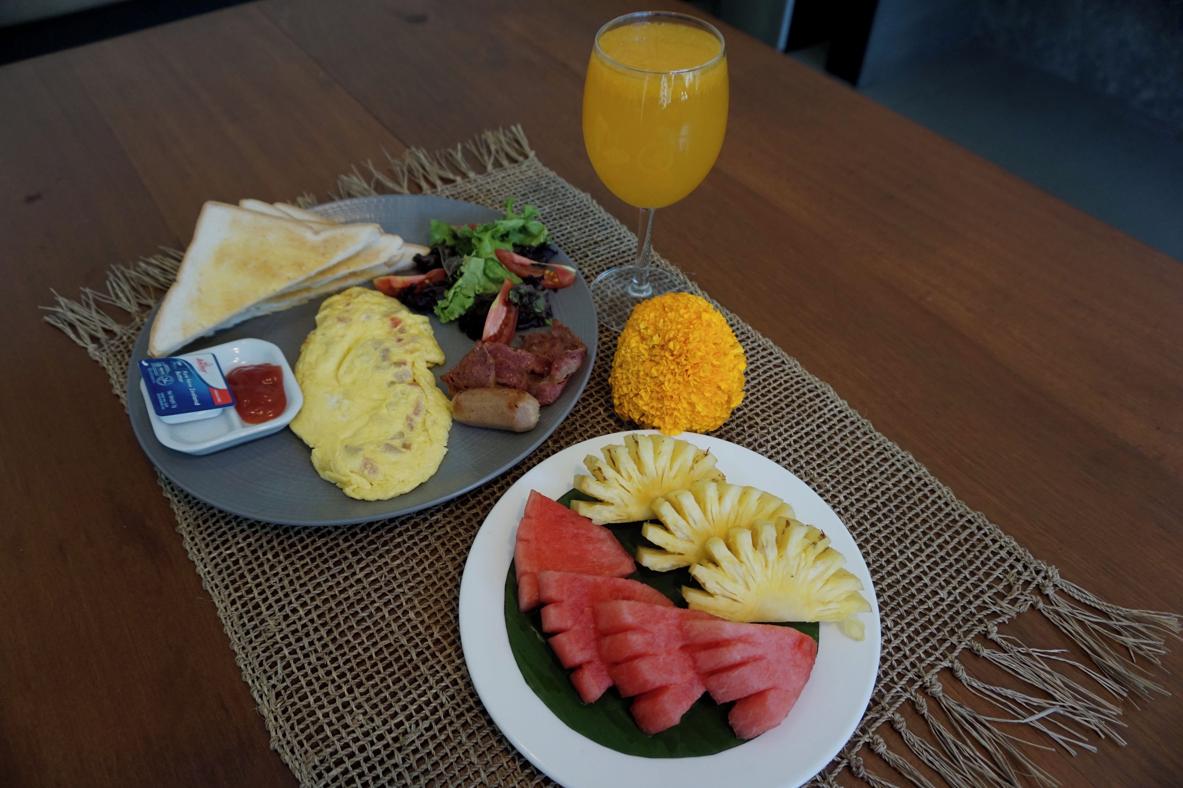 Een ontbijt bord met toast, eieren, spek, een salade en een glas sinaasappelsap.