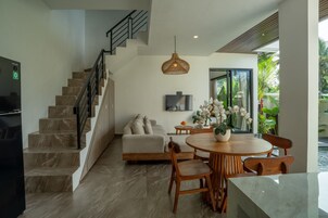 Una sala de estar moderna con una escalera, un comedor y un televisor montado en la pared.