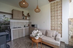 Cozinha moderna com sofá e mesa, micro-ondas e objetos decorativos.