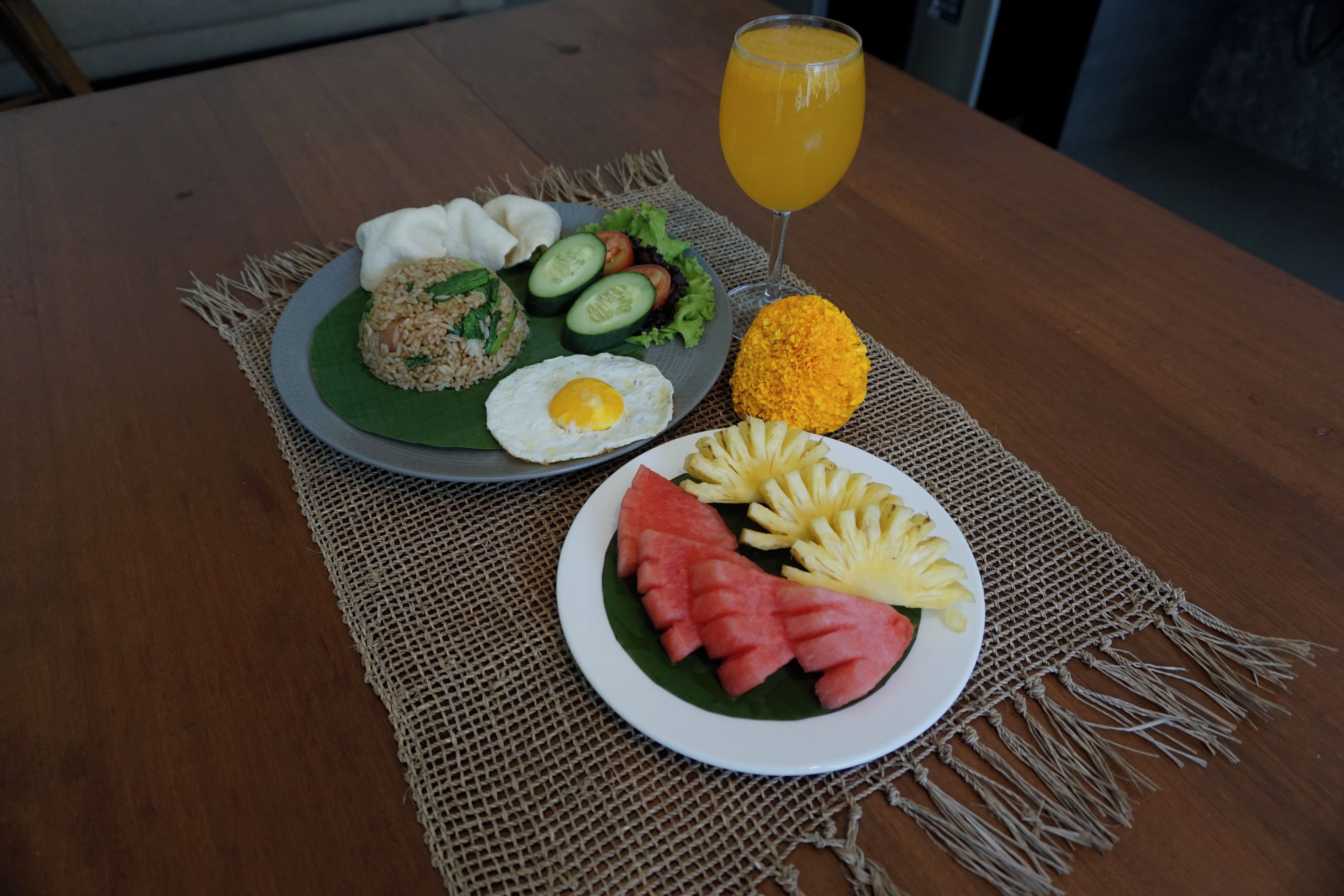 A meal with rice, egg, vegetables, and a glass of orange juice on a table.