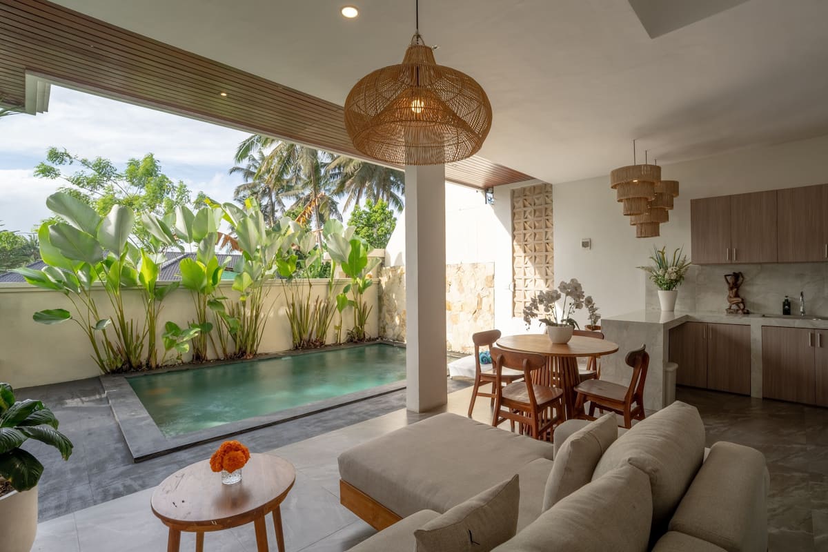 Un área de estar moderna con piscina, mobiliario exterior y cocina.