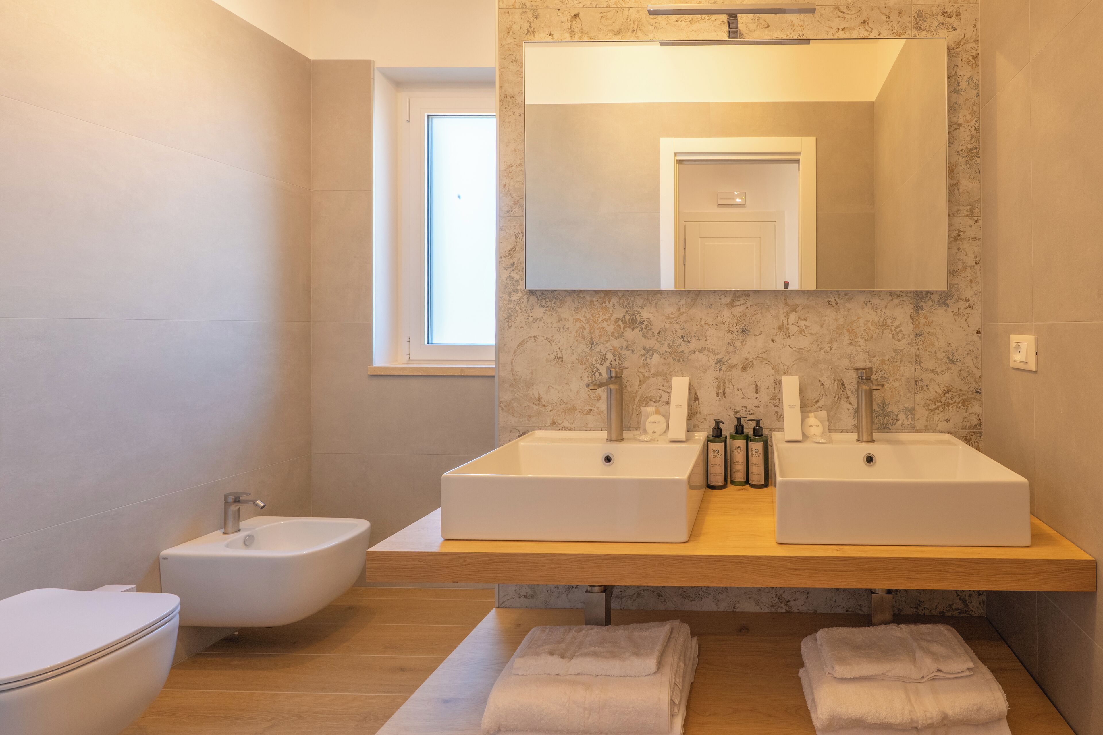 A modern bathroom with two sinks, a bidet, and a large mirror.