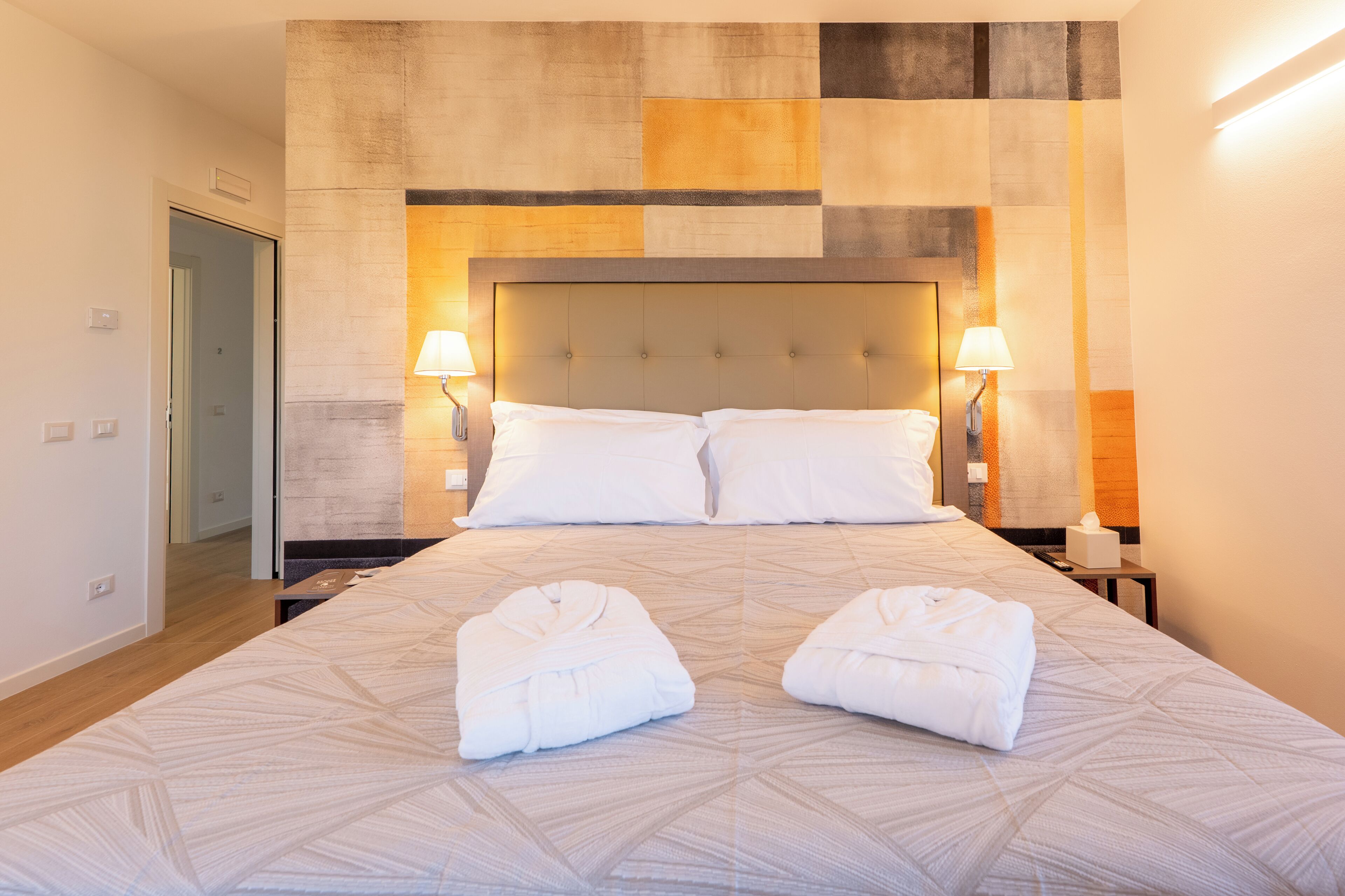 Una camera d'albergo con un letto grande, due abat-jour e due asciugamani sul letto.