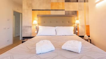 Una camera d'albergo con un letto grande, due abat-jour e due asciugamani sul letto.