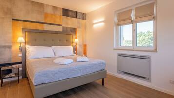 Quarto moderno com cama grande, abajures, janela com persianas e radiador.
