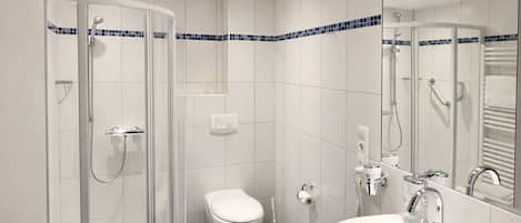 A bathroom with a glass-enclosed shower, a toilet, a sink, and a mirror.