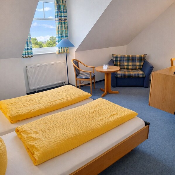 Une chambre avec deux lits, un canapé, une petite table et une chaise.
