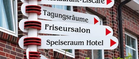 A directional signpost with multiple arrows pointing to various hotel and restaurant locations.